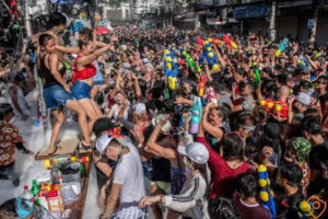 Crowds celebrating Songkran in Chiang Mai with water guns, foam, and dancing during Thailand’s New Year festival.