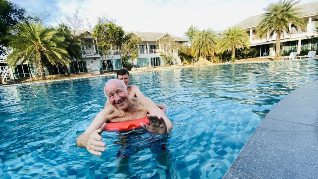 Older residents enjoying pool-based exercise and social activities at a retirement community in Thailand.