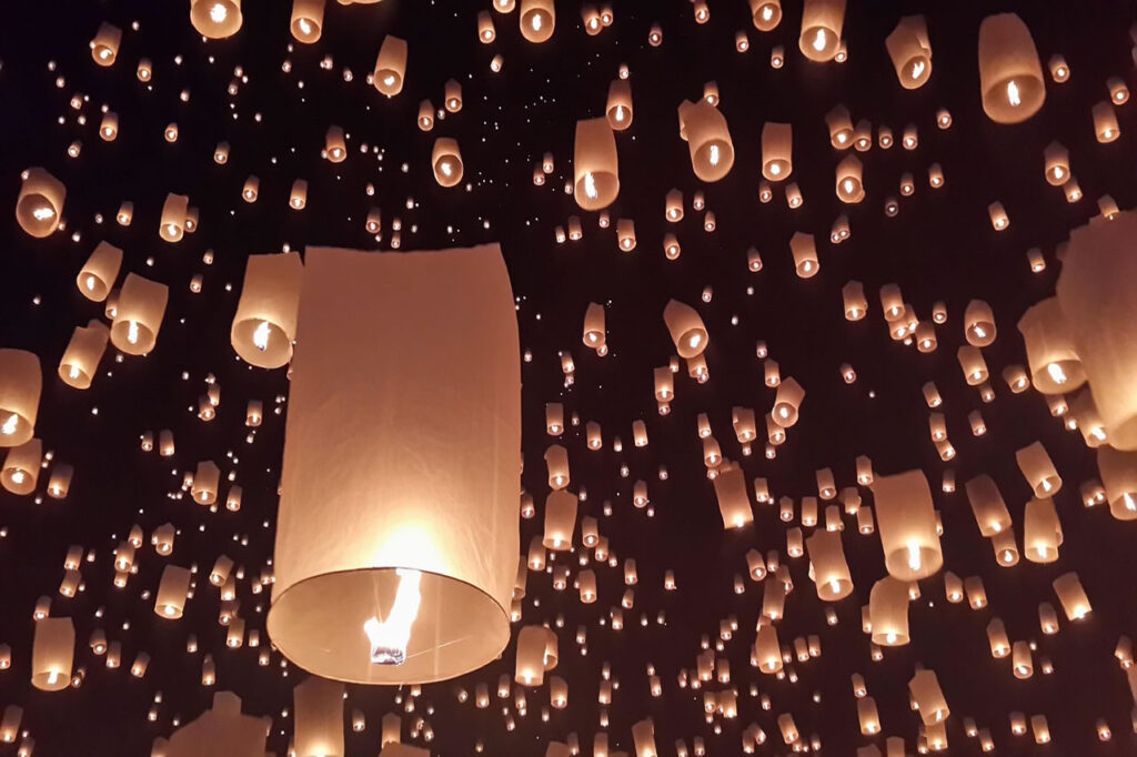 Thousands of glowing sky lanterns rise into the night sky during the Yi Peng celebration in Chiang Mai, part of Thailand’s Loi Krathong festival.