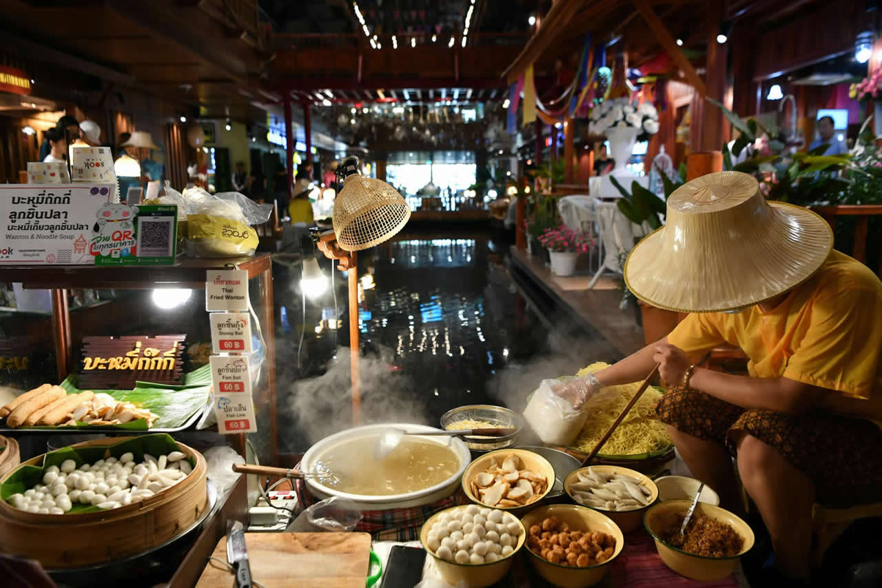 Local Thai street food vendor preparing noodles at a traditional market in Thailand
