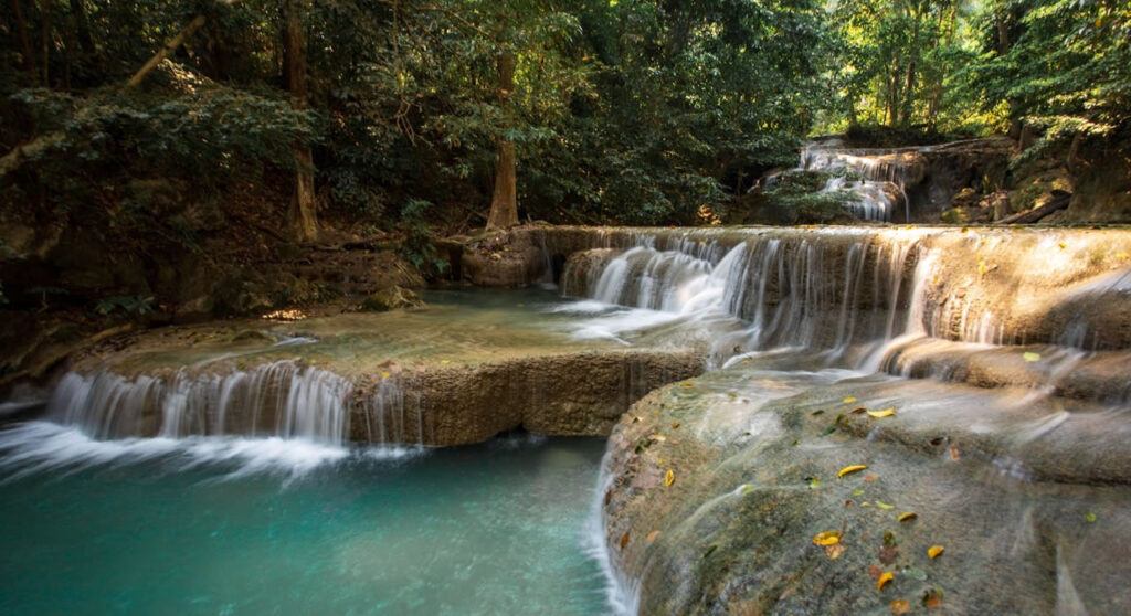 Turquoise waterfall cascading over limestone tiers at Erawan National Park in Kanchanaburi, Thailand