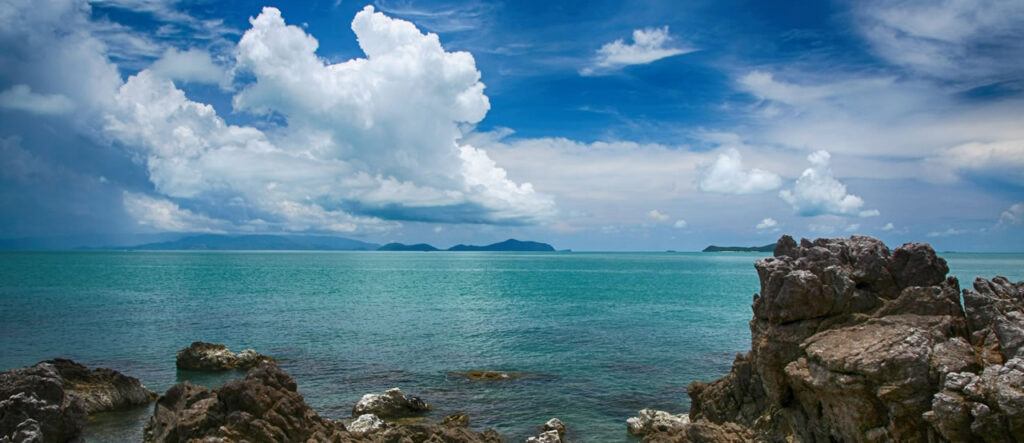 Turquoise sea and dramatic clouds viewed from a rocky shoreline at Hat Khanom, Nakhon Si Thammarat, Thailand