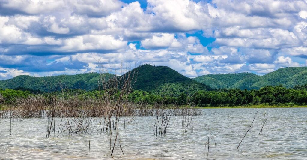 View of forested hills and cloudy sky over a reservoir at Kaeng Krachan National Park, Thailand