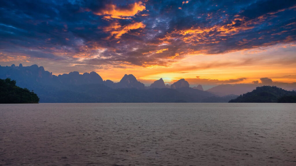 Sunset over limestone cliffs and still waters of Cheow Lan Lake in Khao Sok National Park, Thailand