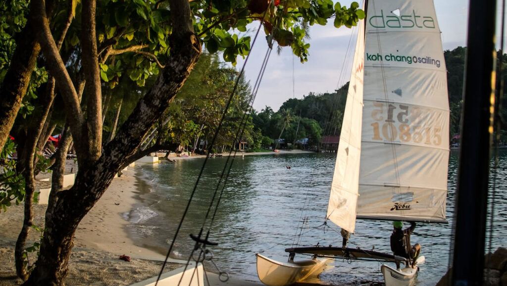 Sailing boat on a calm bay at Koh Chang with lush trees and quiet beach in the background
