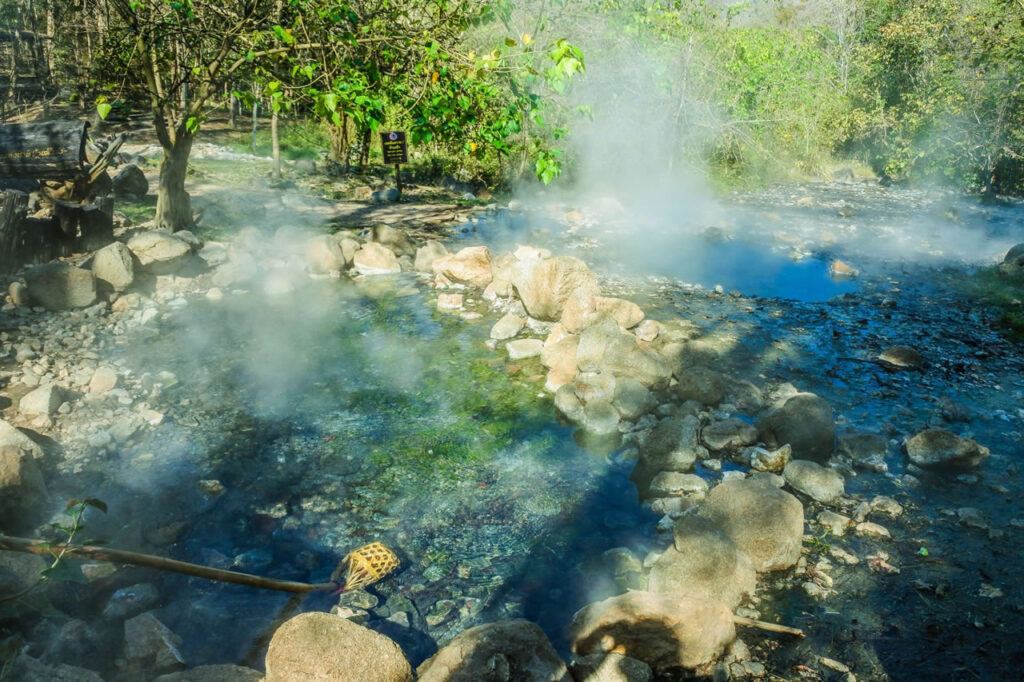 Steaming rock pools at Pai Hot Springs surrounded by forest in northern Thailand