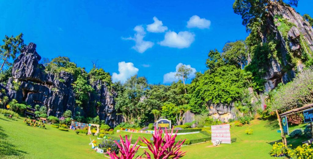 Colorful landscaped garden at Phangam Mountain in Loei, Thailand, surrounded by limestone cliffs and lush greenery under a bright blue sky