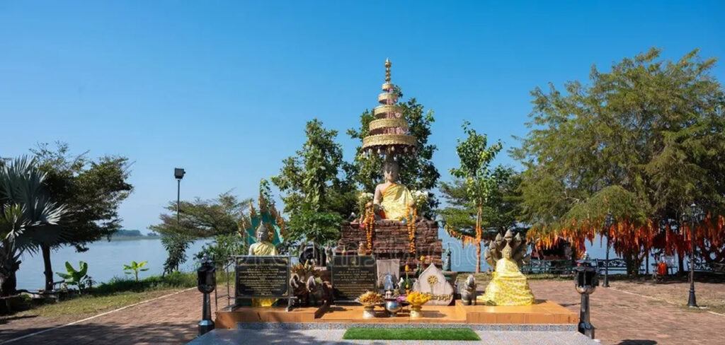 Buddha statue shrine near Wat Si Khom Kham on the banks of Phayao Lake in northern Thailand, surrounded by trees and offerings