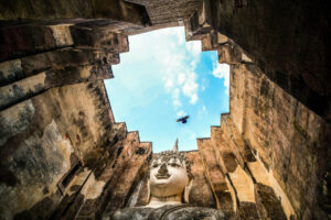 View of the giant seated Buddha statue through stone walls at Wat Si Chum in Sukhothai, Thailand