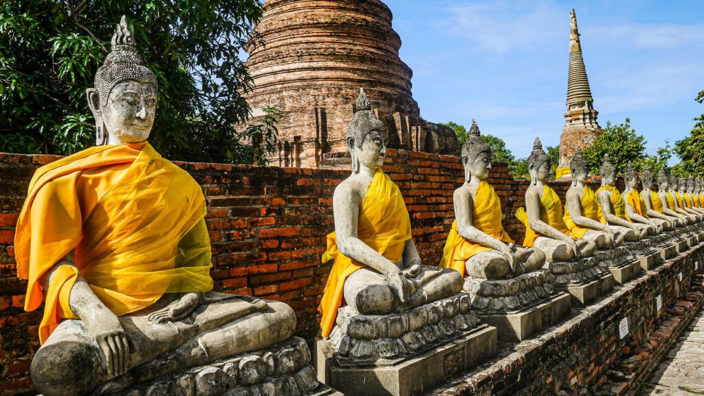 Ancient stone Buddhas draped in yellow robes at Wat Yai Chai Mongkhon, Ayutthaya Historical Park