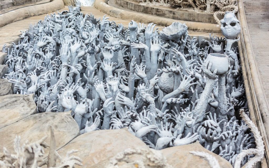Outstretched hands sculpture representing suffering at the White Temple’s bridge to heaven