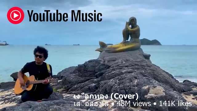 Musician playing guitar beside the Phra Aphai Mani statue on Koh Samet, featured in a YouTube Music video cover of a Thai song