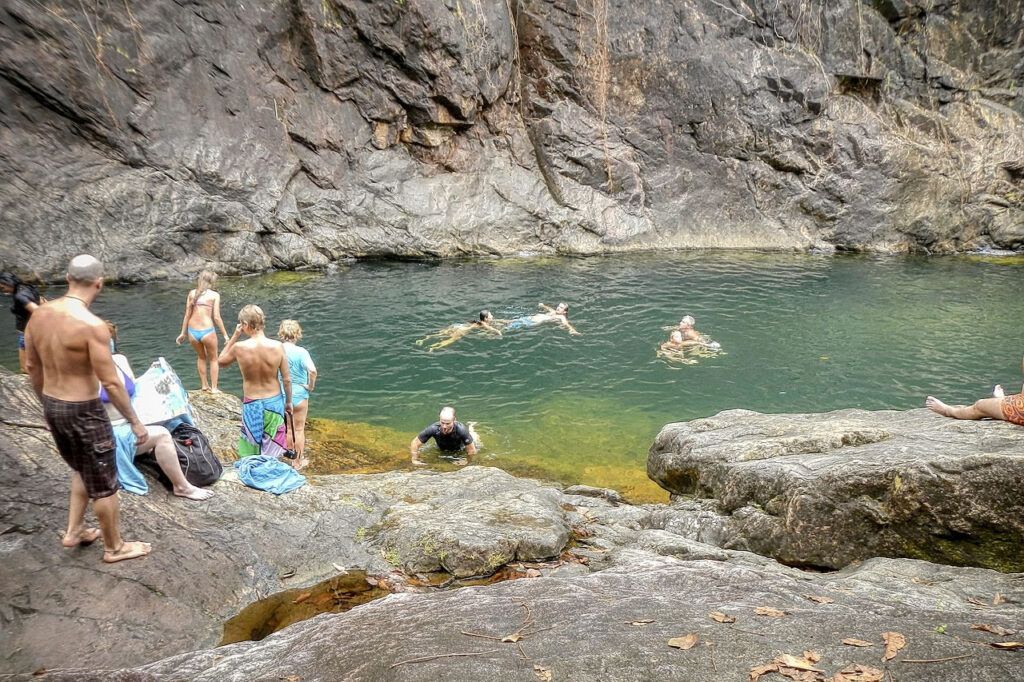 Visitors swimming and relaxing in the plunge pool at Klong Plu Waterfall on Koh Chang, Thailand