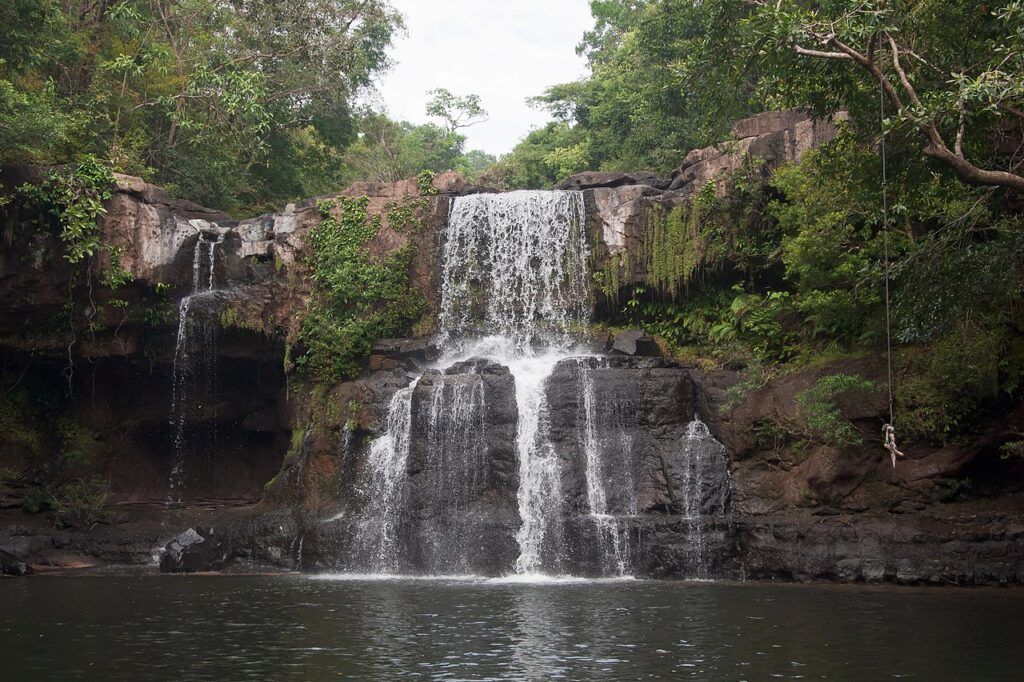 Waterfall on Koh Kood, Thailand, cascading over rocky cliffs into a natural swimming pool, surrounded by lush tropical forest.