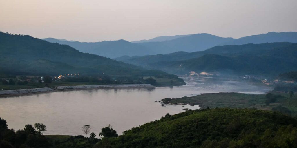 View of the Mekong River and surrounding mountains at the Golden Triangle near Chiang Rai, Thailand, during dusk.