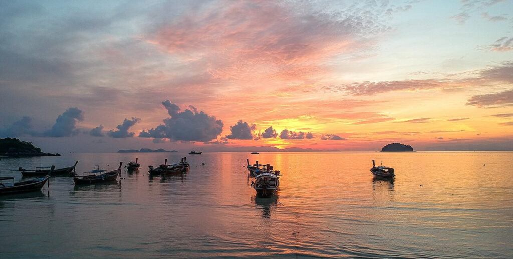 Colorful sunrise over the sea with longtail boats anchored at Koh Lipe, Thailand