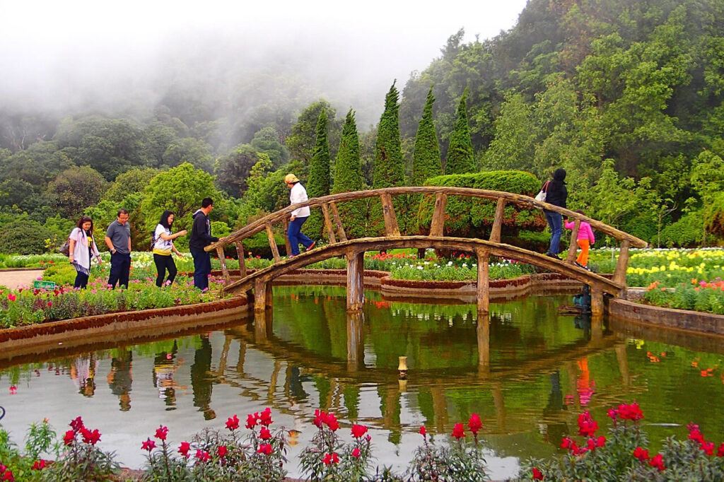 Visitors crossing a wooden bridge in the flower gardens near the Twin Royal Pagodas at Doi Inthanon National Park, Chiang Mai
