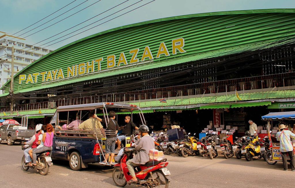 Pattaya Night Bazaar with songthaew taxi and motorbikes outside the market entrance.