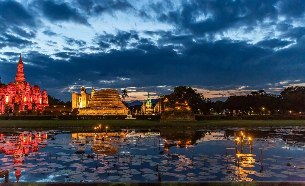 Sukhothai Historical Park illuminated at night during a light show with temples and chedis reflected in the lotus pond, Thailand