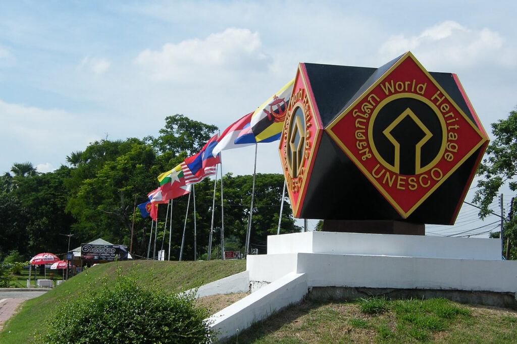 UNESCO World Heritage sign at the entrance of Sukhothai Historical Park, Thailand, with ASEAN flags in the background