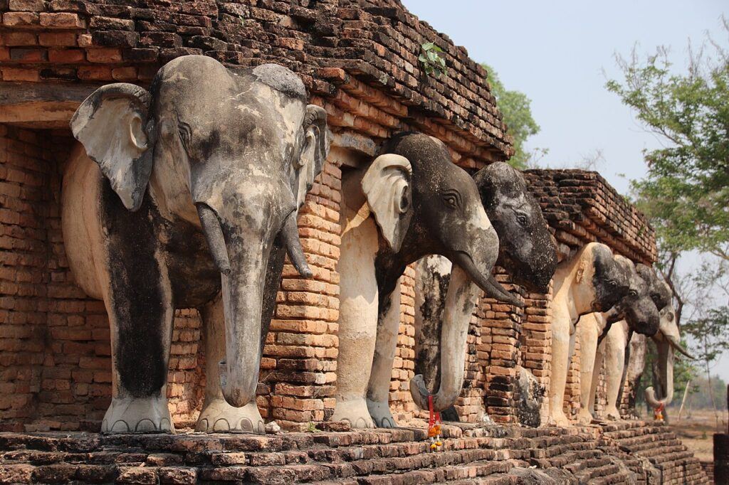 Elephant statues surrounding the base of Wat Chang Lom temple in Sukhothai Historical Park, Thailand