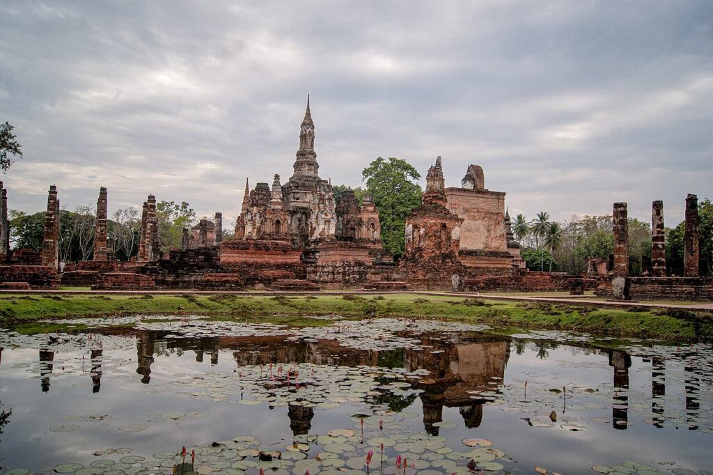 Wat Mahathat temple ruins reflected in a lotus pond at Sukhothai Historical Park, Thailand