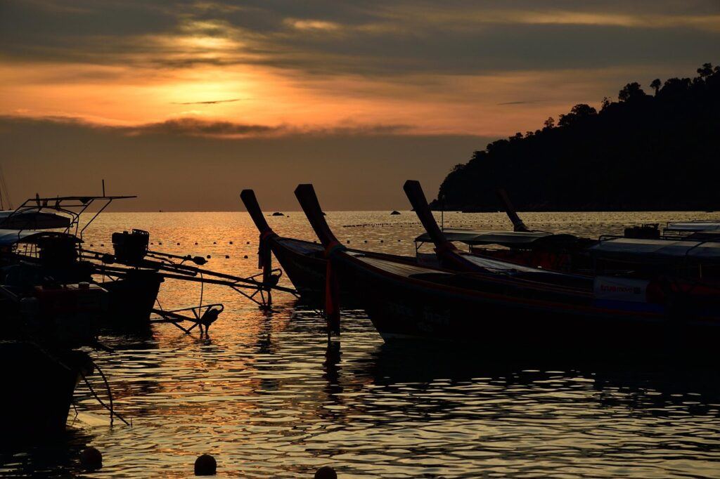 Traditional longtail boats at sunset on a Thai beach