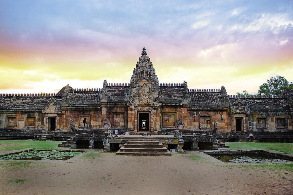 Front view of Phanom Rung temple at sunset with golden sky and lotus ponds in the foreground