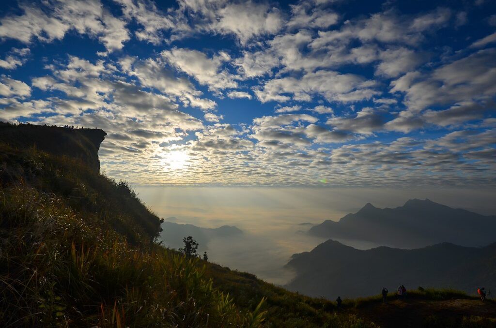 Sunrise over the mist-filled valleys at Phu Chi Fa, Chiang Rai, with dramatic cloud patterns and mountain silhouettes.