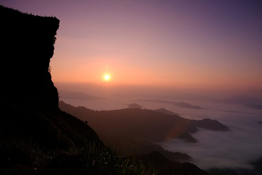 Sunrise over Phu Chi Fa with a purple horizon and layers of mist-covered mountains in northern Thailand