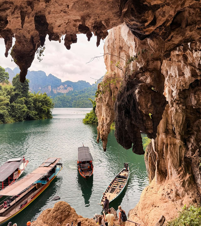 Longtail boats at a limestone cave entrance on Cheow Lan Lake in Khao Sok National Park