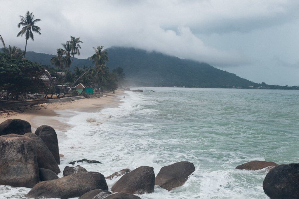 Waves hitting a rocky beach in Koh Samui, Thailand during cloudy monsoon weather