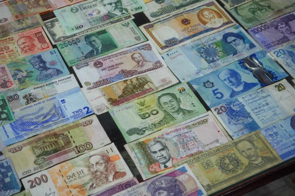 Different currencies including Thai baht representing financial preparation for moving to Thailand