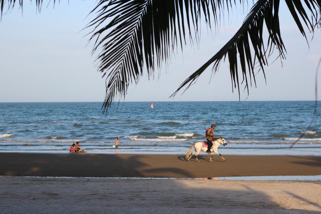 Family enjoying Hua Hin beach with children playing and horse riding