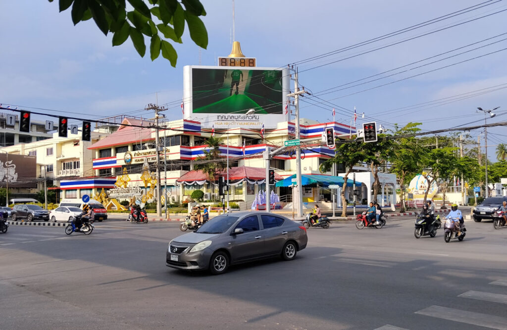 Traffic and motorbikes passing the Hua Hin City Municipality building at a busy intersection in Hua Hin, Thailand.