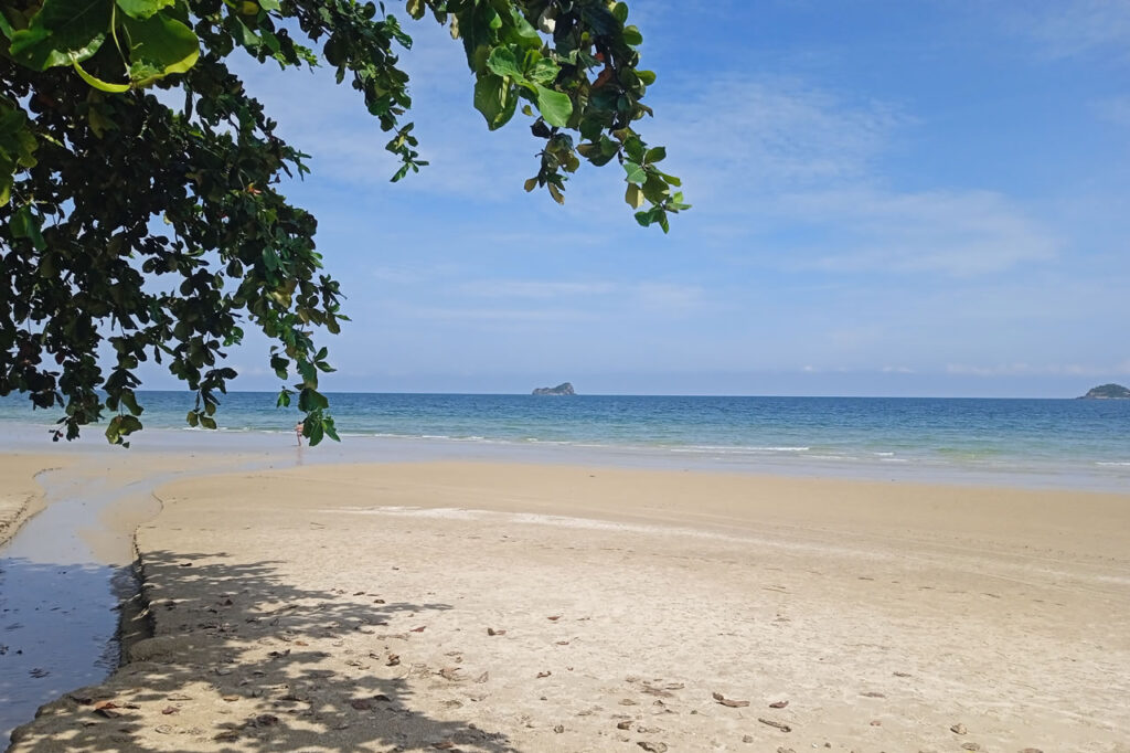 Quiet beach in Khao Tao near Hua Hin with calm sea, shaded trees, and a relaxed coastal atmosphere.