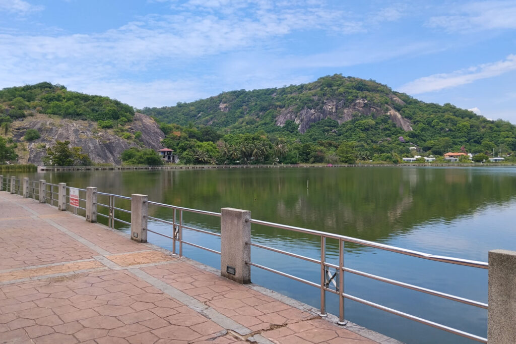Lakeside promenade at Khao Tao with calm water, surrounding hills, and walking paths.