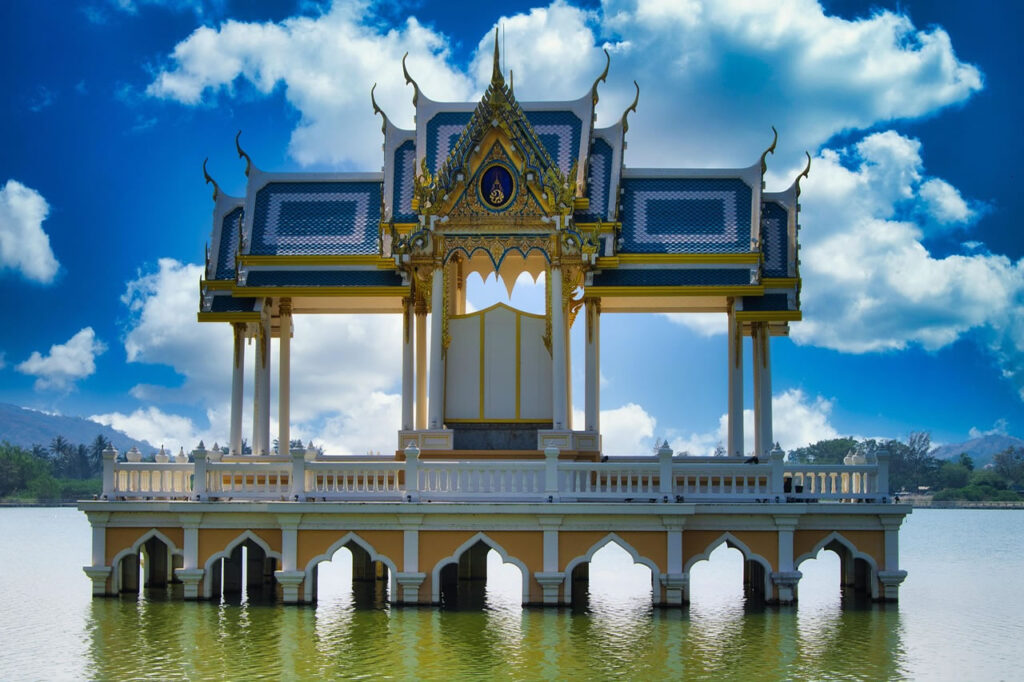 Royal pavilion and lakeside walkway in Khao Tao near Hua Hin surrounded by tropical greenery and calm water.