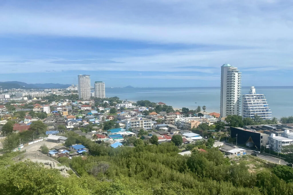 View over Hua Hin showing condos, residential neighborhoods, and the coastline from an elevated viewpoint.
