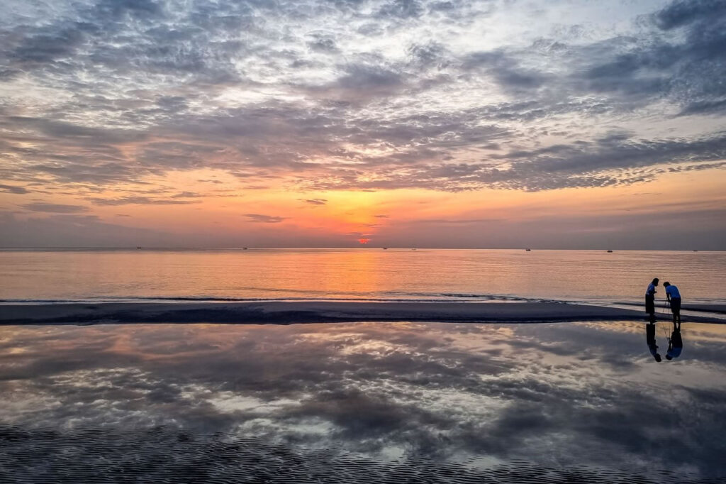 Sunrise over Hua Hin Beach reflecting on the wet sand, representing the relaxed lifestyle that attracts many retirees to Hua Hin, Thailand.