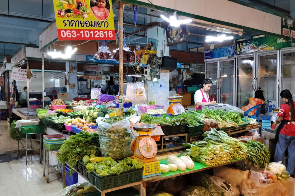 Fresh vegetable stall at a traditional Thai market, illustrating small businesses, daily commerce, and household economic activity in Thailand.