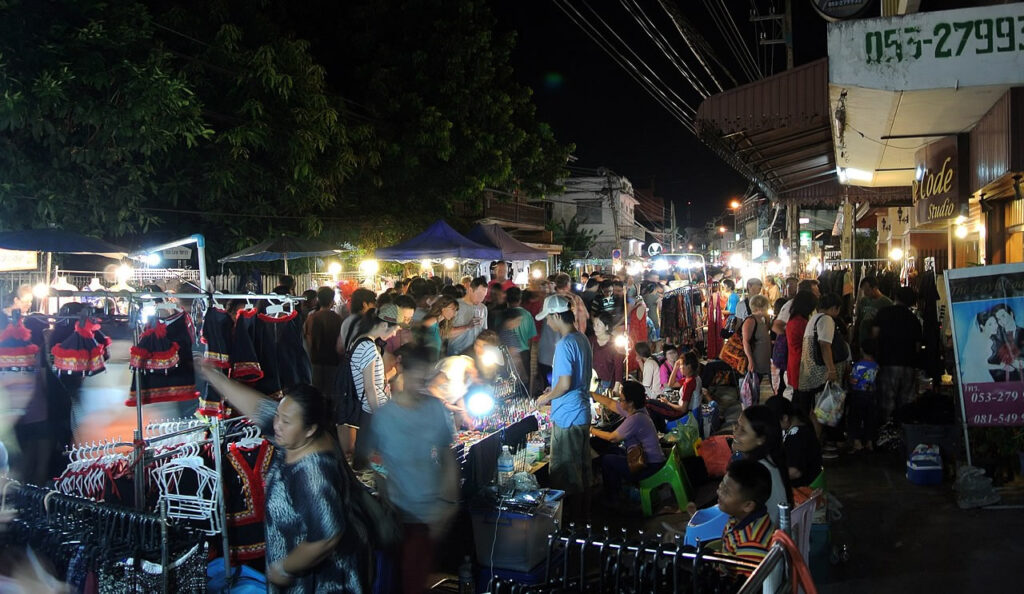 Busy night market with clothing stalls and shoppers in Chiang Mai