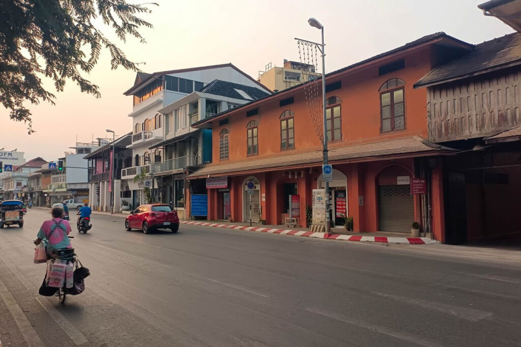 Everyday street scene in Chiang Mai with a bicycle, motorbikes and traditional shopfronts.