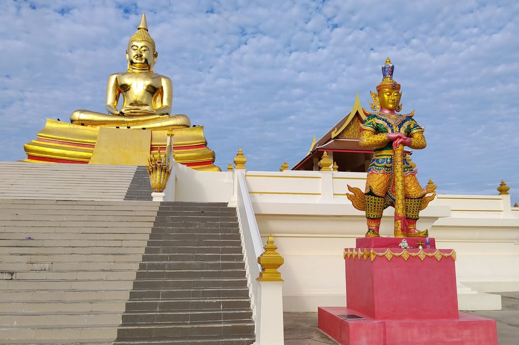 Golden Buddha and guardian statue at Wat Huay Mongkol near Hua Hin