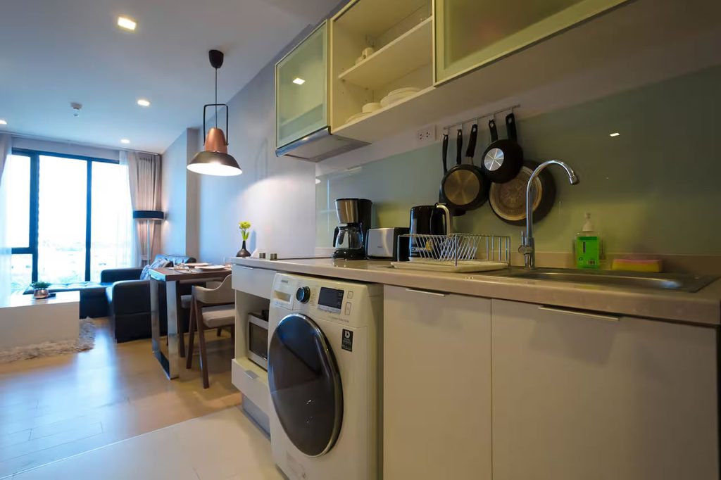 Kitchen with fitted cabinets, sink and washing machine in a condo at The Astra, Chiang Mai