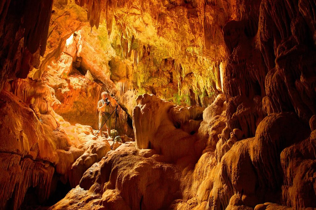 Photographer among stalactites and limestone formations inside Kaew Cave in Khao Sam Roi Yot National Park.