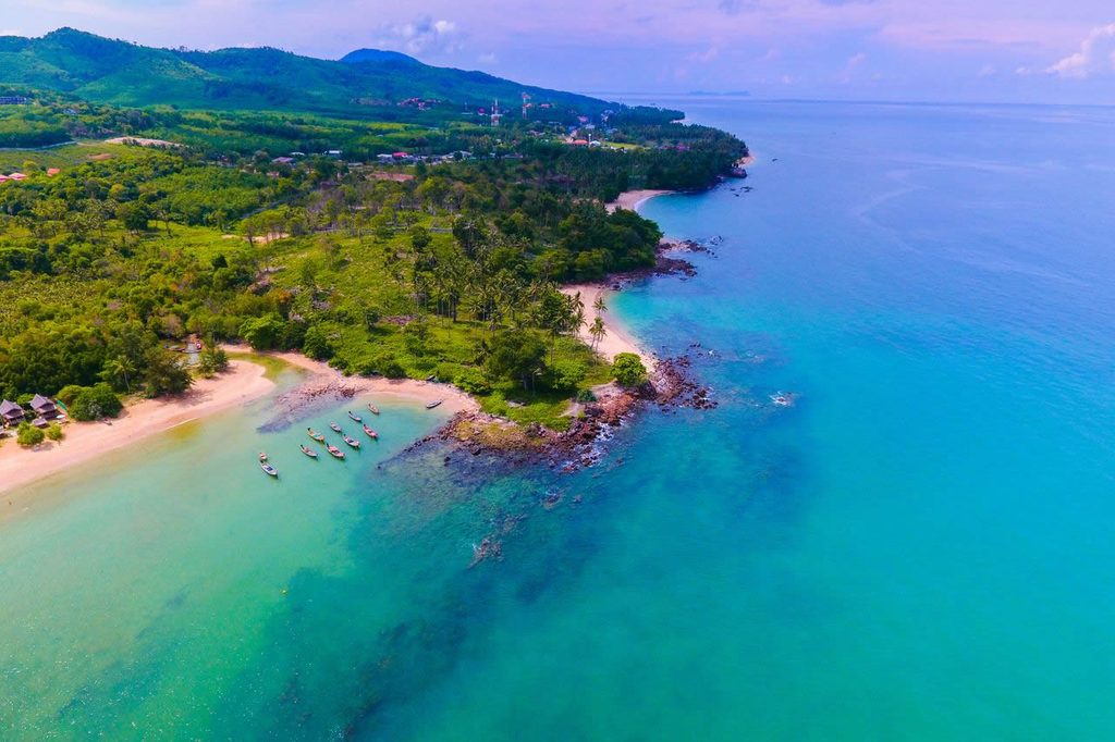Aerial view of sandy coves, rocky headlands and green hills along Koh Lanta’s coast.