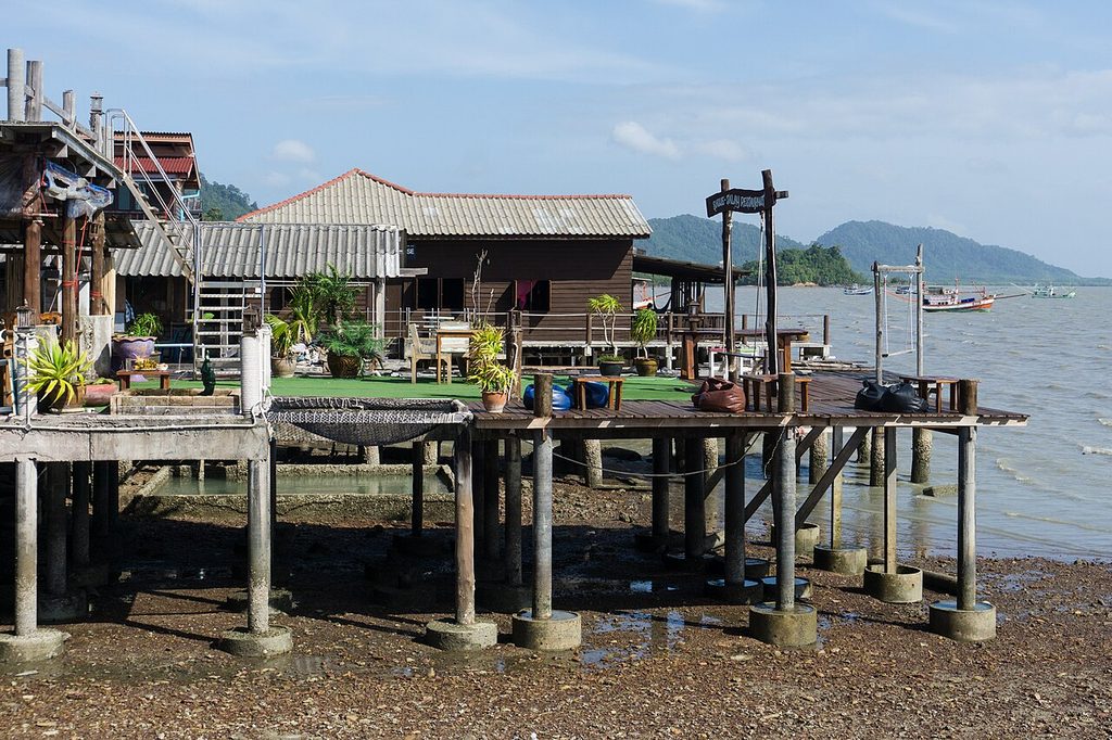 Wooden waterfront buildings on stilts above the exposed shoreline in Lanta Old Town, Koh Lanta.
