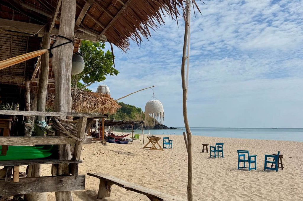 Rustic thatched beach bar with tables and chairs on the sand overlooking the sea on Koh Lanta.