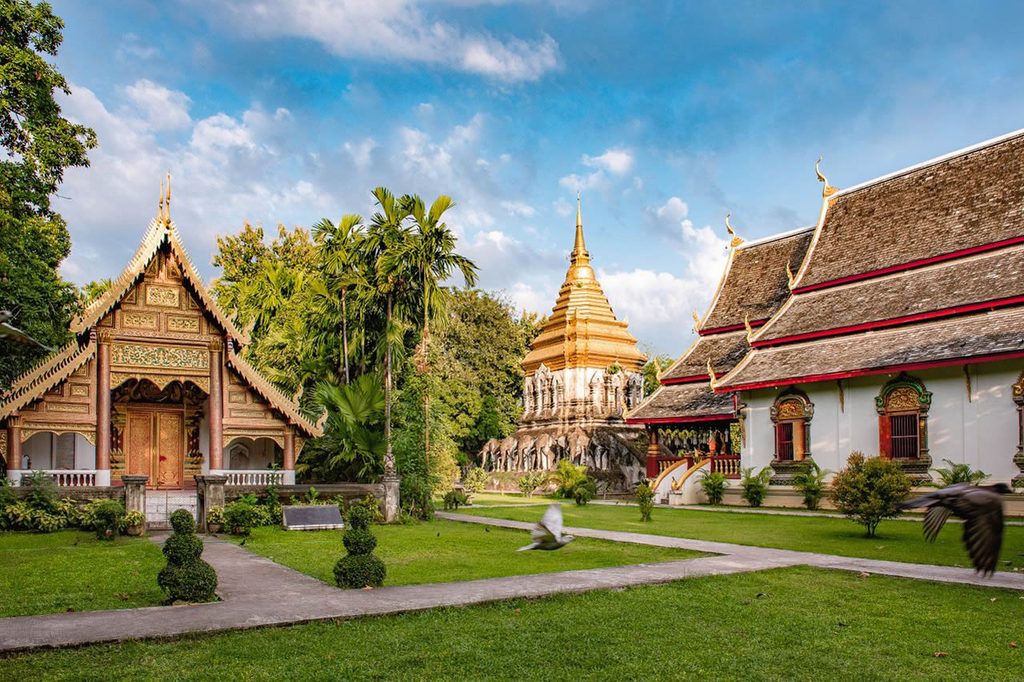 Temple buildings and a golden chedi overlooking the gardens at Wat Chiang Man in Chiang Mai.
